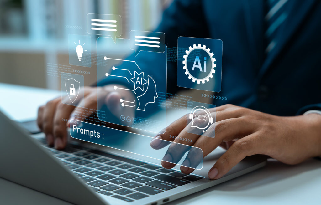ラップトップでタイピングする手元と、その上に表示された AI・プロンプト入力欄のグラフィック