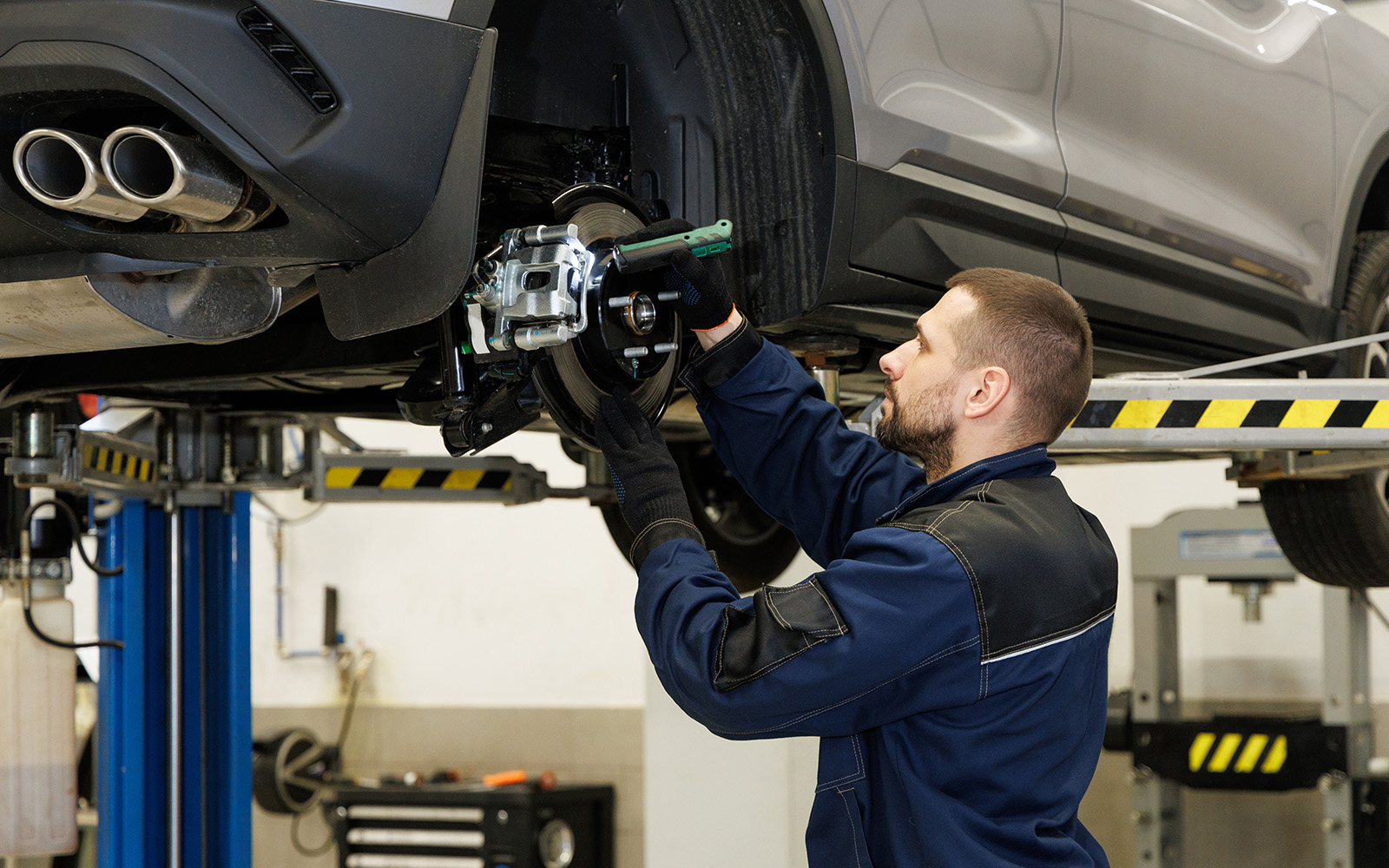 整備工場で車のブレーキを点検する整備士