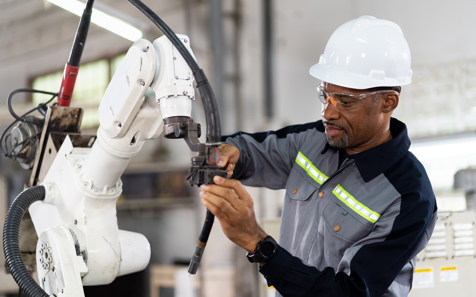 工場でロボットアームを操作する作業員