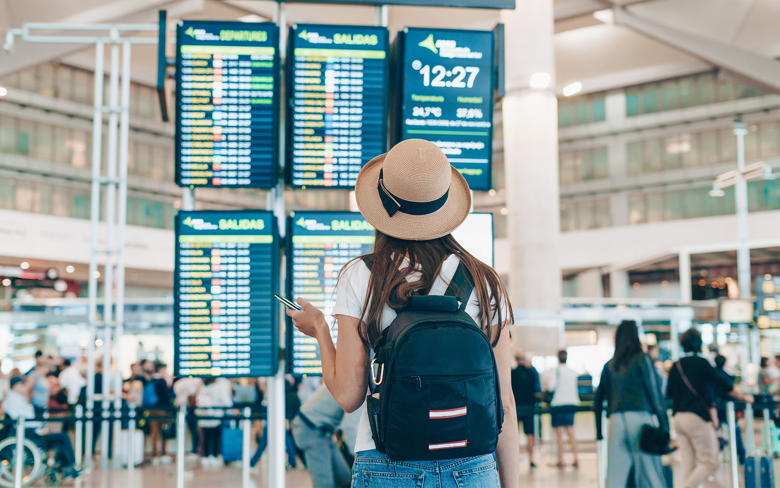 空港の出発案内板を確認する旅行者