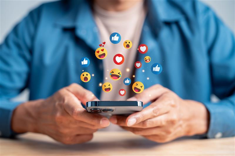 男性がスマホを持っていて、スマホからアイコンがあふれている