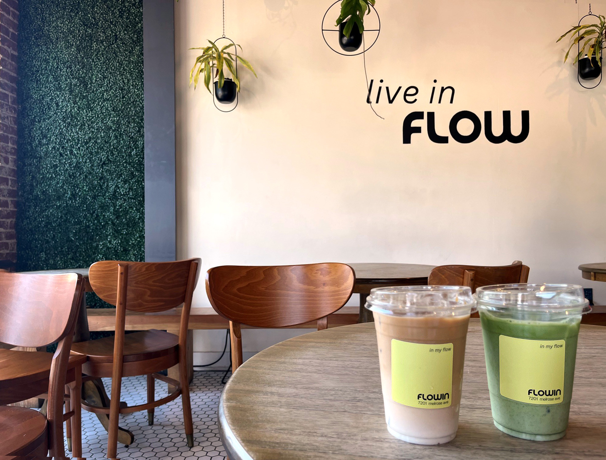 Flowin Cafeの店内、"live in FLOW"の壁アートとテーブルに置かれたドリンク