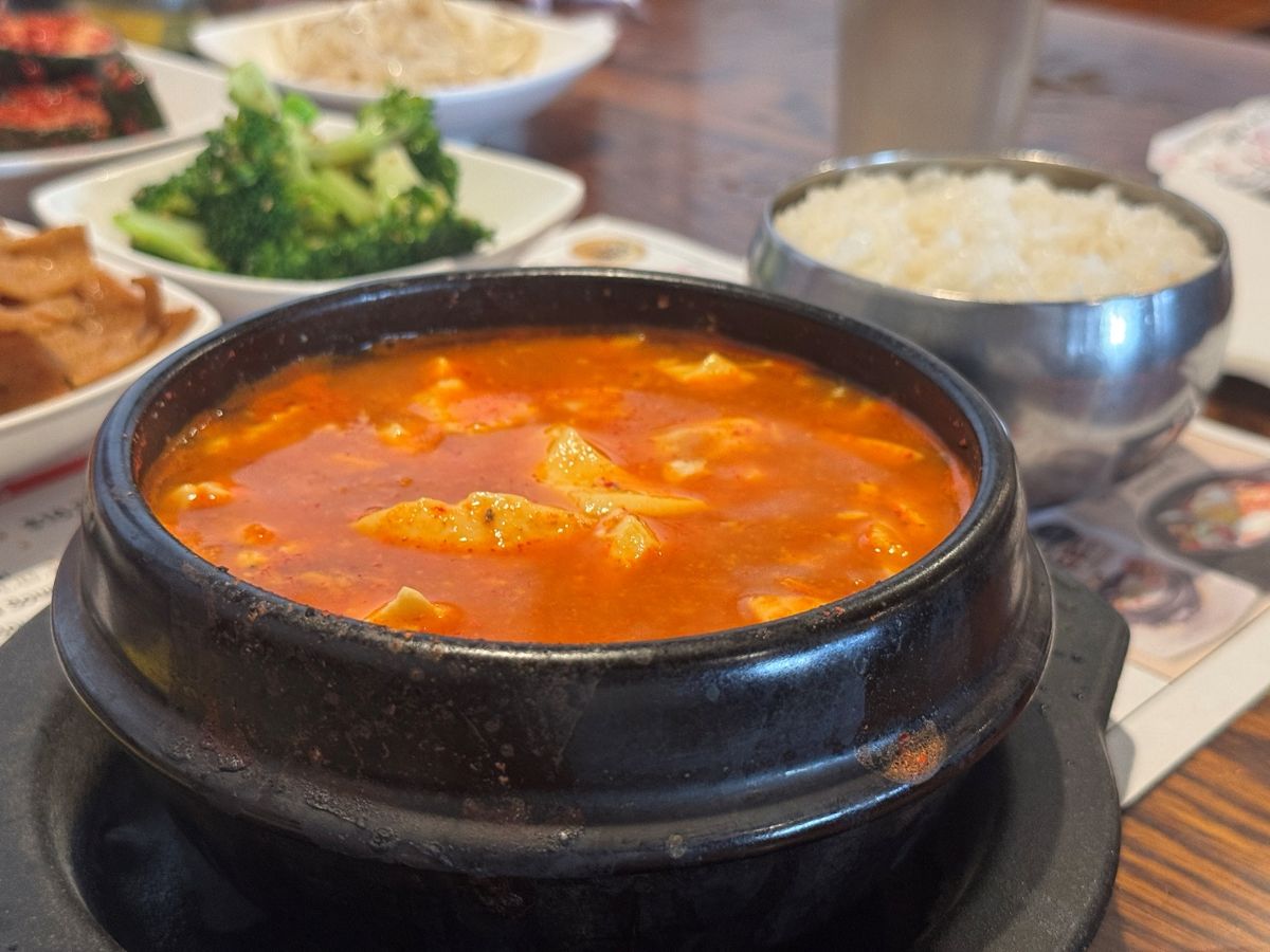 石鍋に入った真っ赤なスンドゥブとご飯、付け合わせ