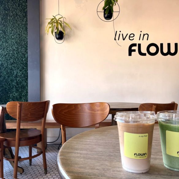 Flowin Cafeの店内、"live in FLOW"の壁アートとテーブルに置かれたドリンク